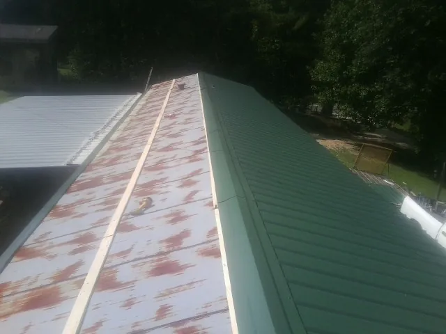 Old rusted panels beside newly installed green metal roofing — Wind Damage Roof Repair by Roofing Brothers in Daytona Beach