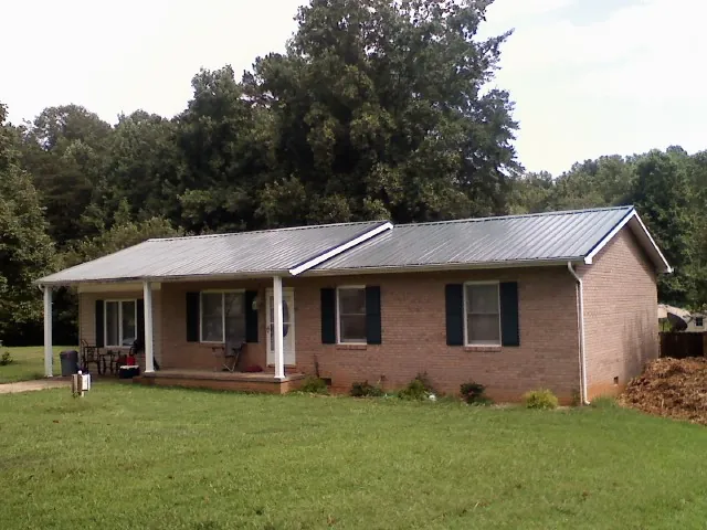 Gray metal roof on a brick ranch house with a side carport in Daytona Beach