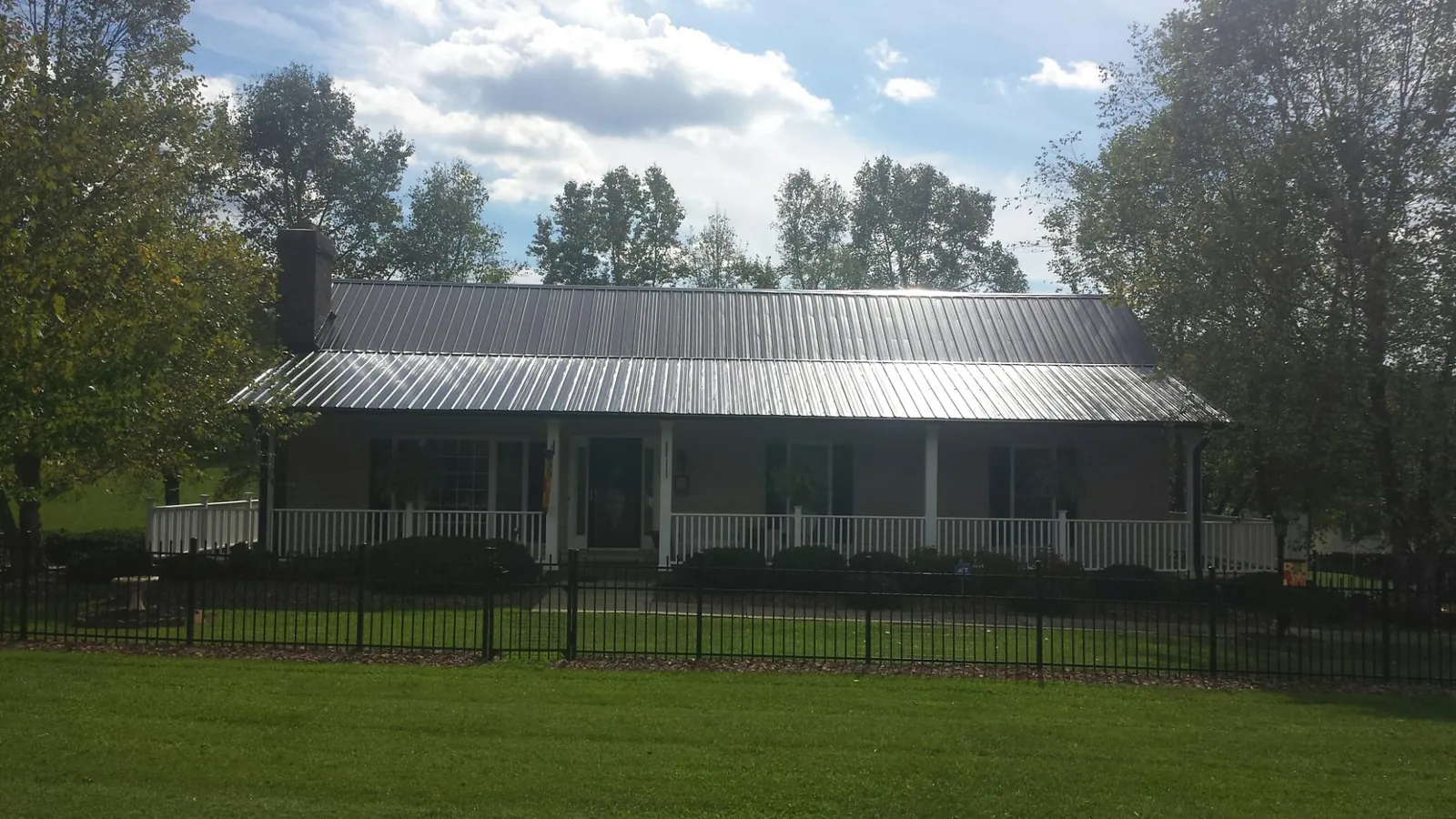 Gray metal roof on a brick ranch with a full width front porch — Gutter Guard Installation work by our crew in Daytona Beach