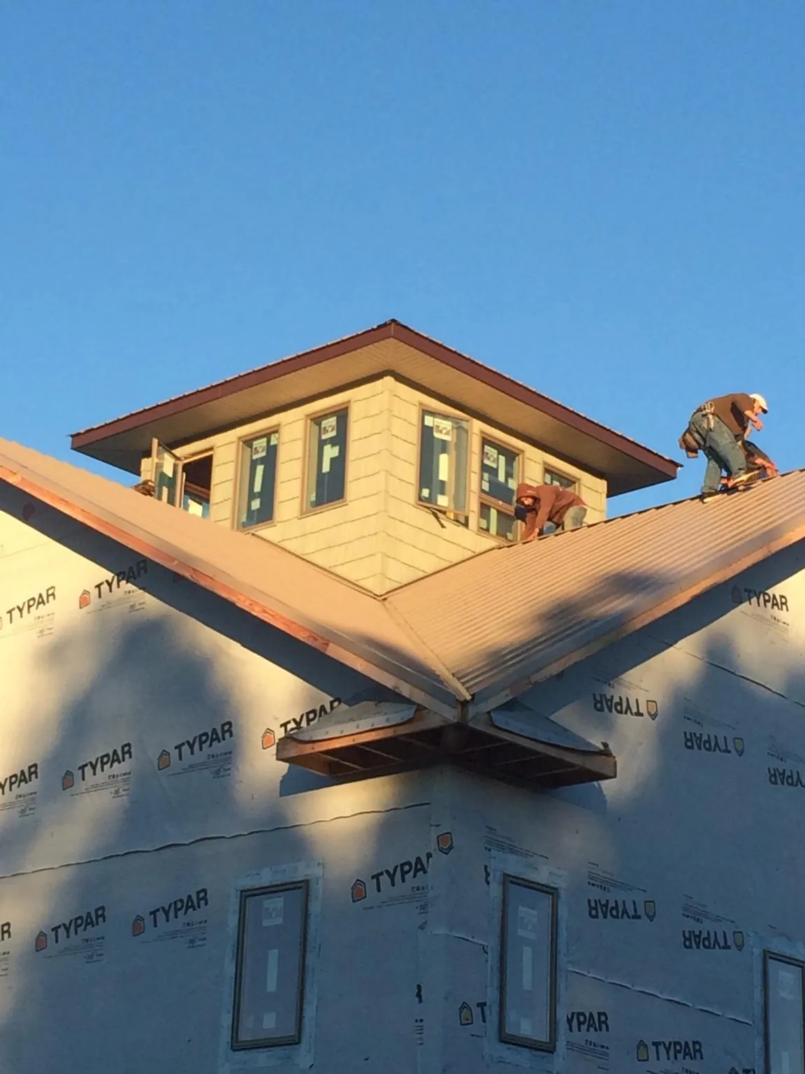 Roofers working around a rooftop cupola on a new metal roof at sunset — Roof Waterproofing in Daytona Beach by Roofing Brothers